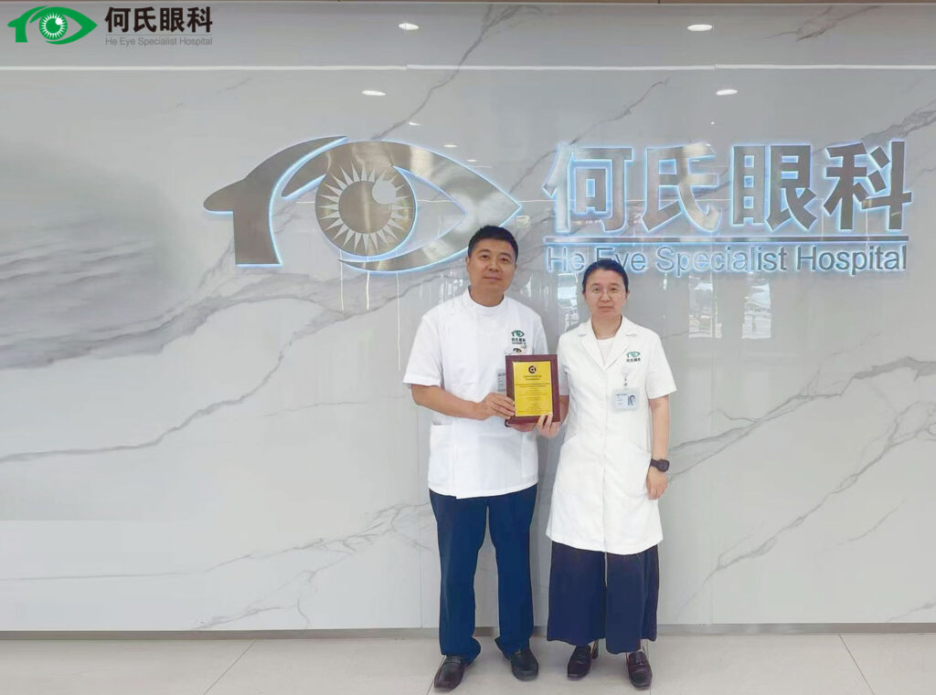 Two doctors standing in front of a sign that says HE Eye Specialist Hospital holding a plaque.