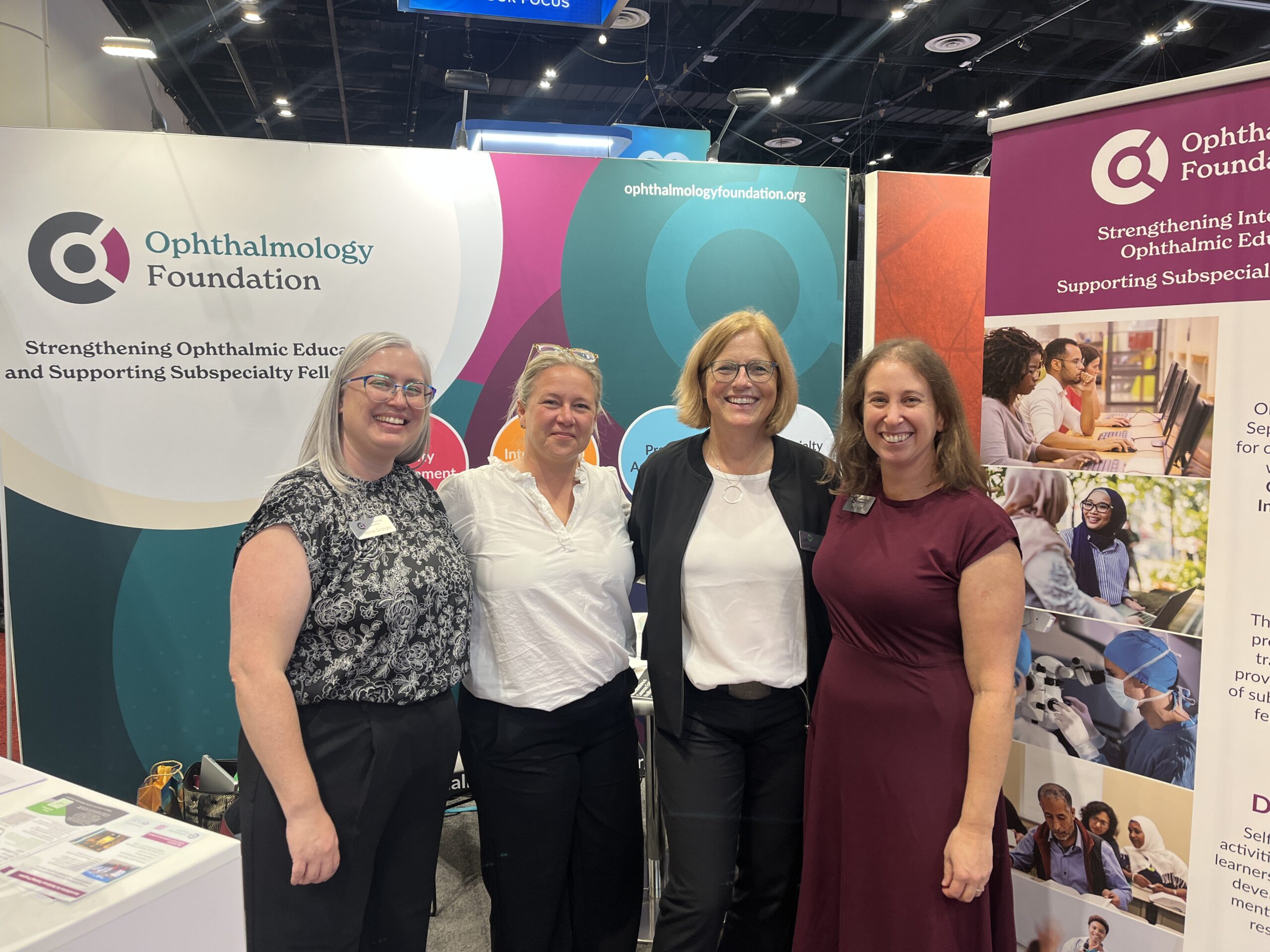 Four women standing in front of the Ophthalmology Foundation booth at a conference exhibition.