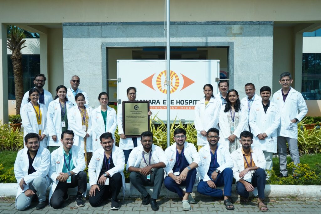 Group of doctors in front of Sankara Eye Hospital India holding a plaque